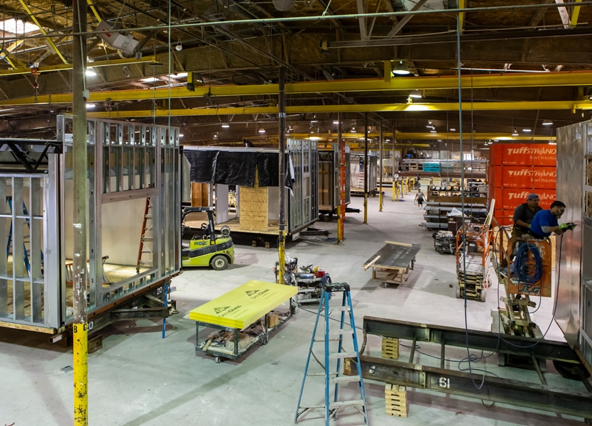Modular construction plant interior with various stages of module completion on the assembly line
